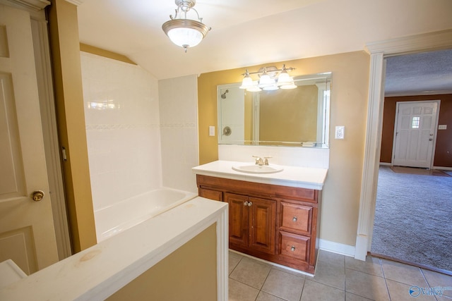 bathroom featuring tile patterned flooring, vanity, lofted ceiling, and a bathing tub