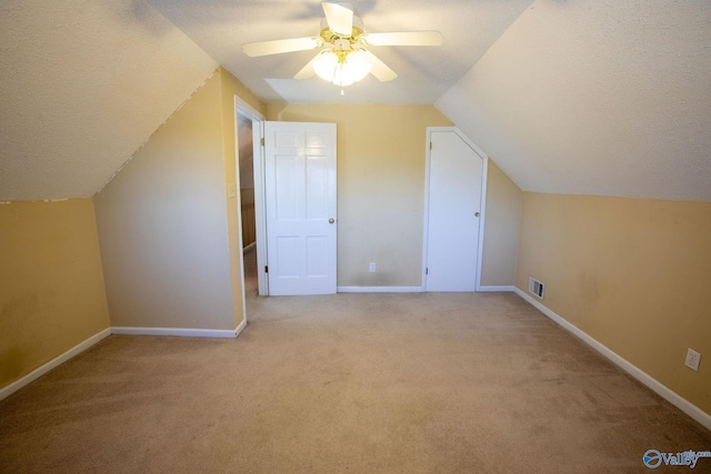 additional living space featuring vaulted ceiling, light carpet, ceiling fan, and a textured ceiling