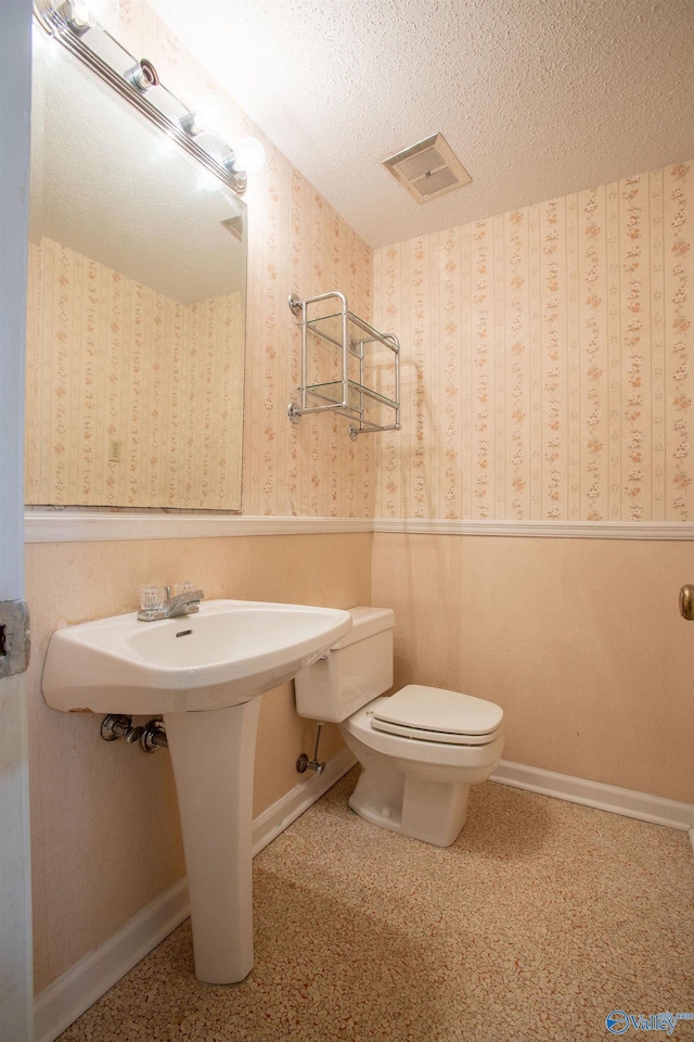 bathroom with toilet and a textured ceiling