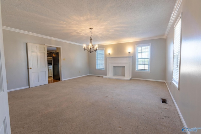 unfurnished living room with crown molding, an inviting chandelier, carpet floors, a textured ceiling, and a brick fireplace