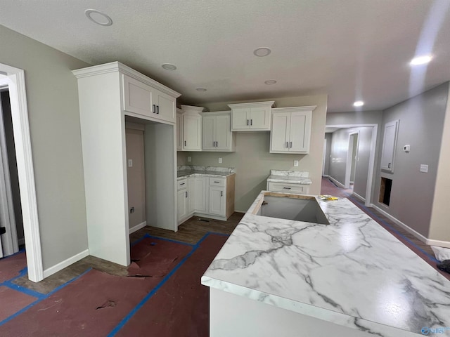 kitchen featuring a textured ceiling, sink, and white cabinetry