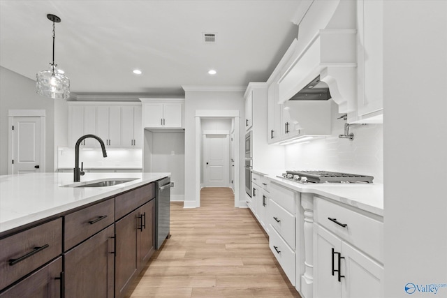 kitchen featuring white cabinets, sink, hanging light fixtures, dark brown cabinetry, and stainless steel appliances