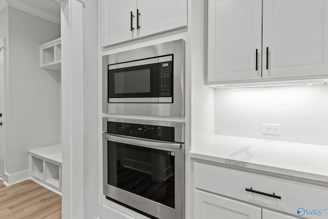 kitchen with light stone countertops, tasteful backsplash, stainless steel appliances, crown molding, and white cabinetry