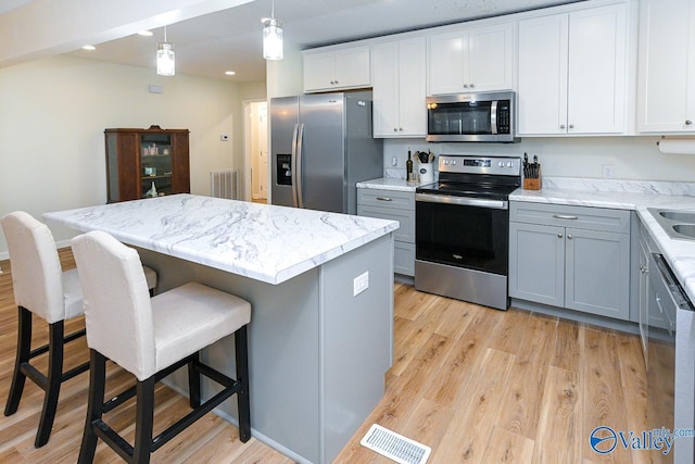 1409 8th Ave SE, Decatur, AL 35601 - kitchen featuring appliances with stainless steel finishes, light wood-style floors, a kitchen breakfast bar, a kitchen island, and recessed lighting