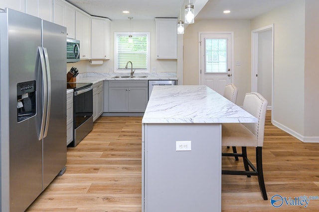 1409 8th Ave SE, Decatur, AL 35601 - kitchen with appliances with stainless steel finishes, a sink, a breakfast bar, a center island, and light wood-type flooring