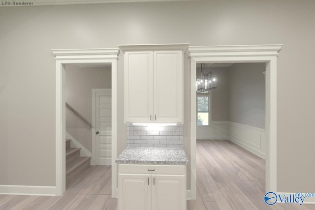 kitchen featuring white cabinetry, tasteful backsplash, decorative light fixtures, light wood-type flooring, and a notable chandelier