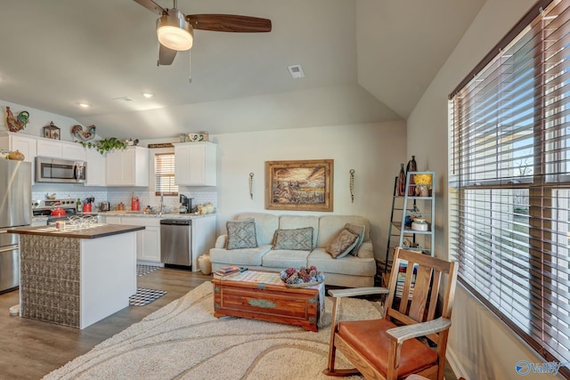 living area with light wood finished floors, visible vents, lofted ceiling, recessed lighting, and a ceiling fan