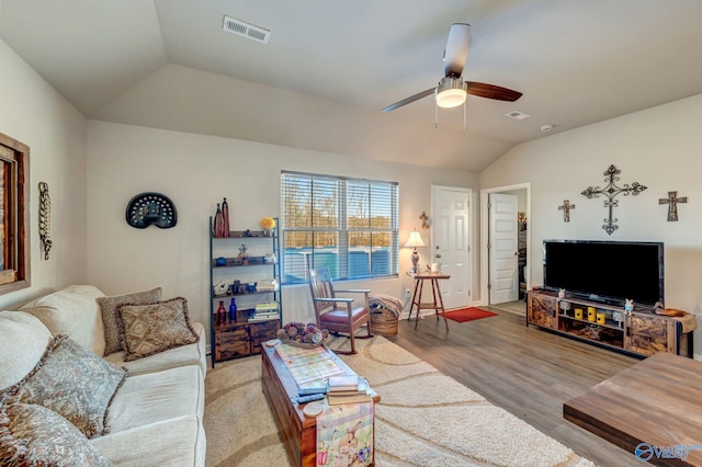 living area featuring visible vents, baseboards, lofted ceiling, wood finished floors, and a ceiling fan