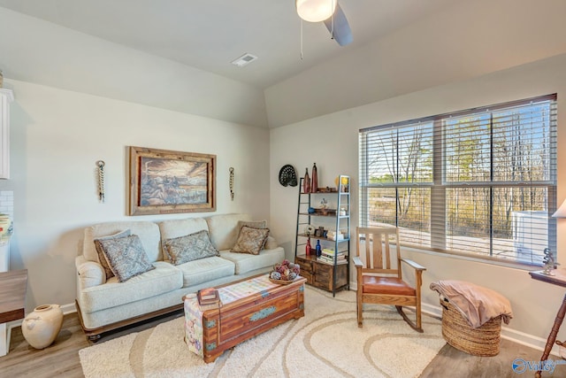 living area featuring visible vents, baseboards, ceiling fan, lofted ceiling, and wood finished floors