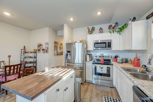 kitchen with light wood-style flooring, stainless steel appliances, white cabinets, tasteful backsplash, and butcher block counters