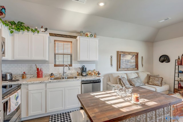 kitchen featuring visible vents, backsplash, vaulted ceiling, stainless steel appliances, and a sink