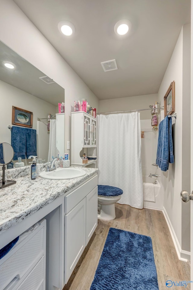 bathroom featuring vanity, wood finished floors, visible vents, shower / tub combo, and toilet