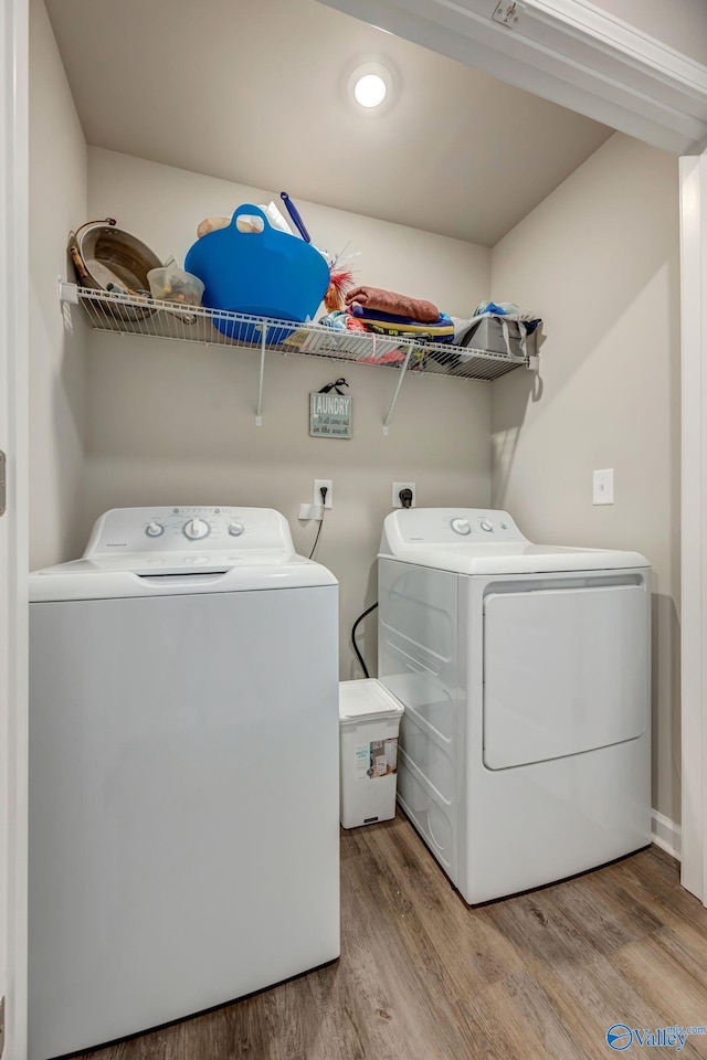 laundry area featuring washer and clothes dryer, laundry area, and wood finished floors