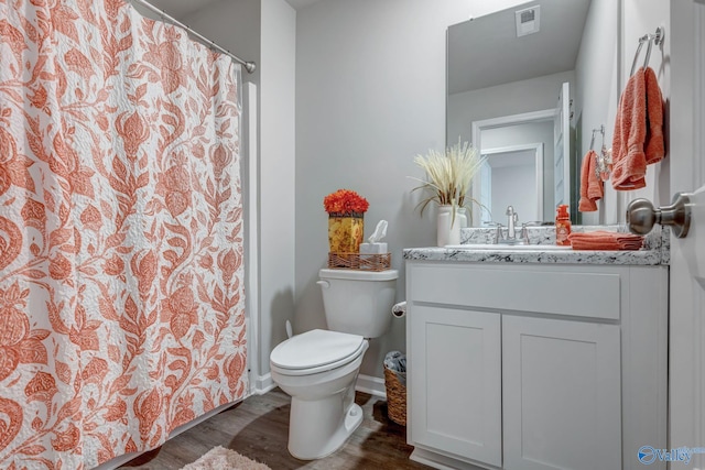 bathroom featuring vanity, wood finished floors, visible vents, baseboards, and toilet