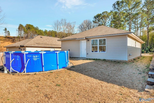 exterior space with an outdoor pool, a lawn, and a shingled roof