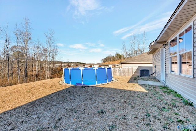 view of yard with a pool, fence, and central AC