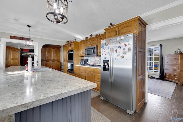 kitchen with stainless steel appliances, a notable chandelier, pendant lighting, wood-type flooring, and ornamental molding