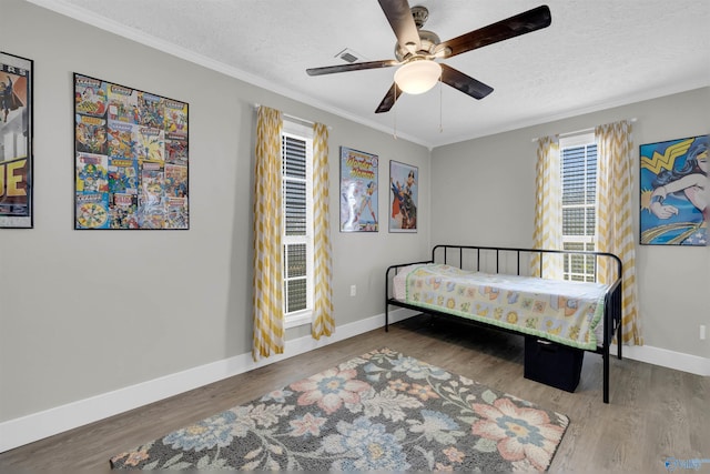 bedroom featuring a textured ceiling, ceiling fan, wood-type flooring, and crown molding