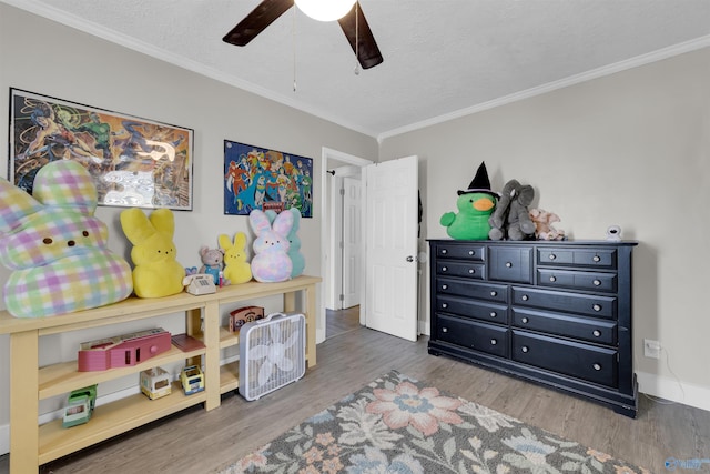 rec room featuring crown molding, ceiling fan, wood-type flooring, and a textured ceiling