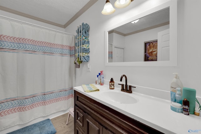 bathroom featuring hardwood / wood-style flooring, vanity, a textured ceiling, and ornamental molding