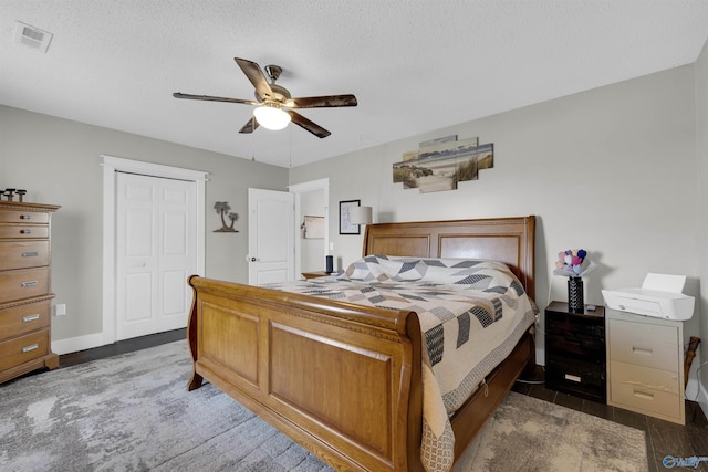 bedroom featuring a textured ceiling, a closet, ceiling fan, and dark wood-type flooring