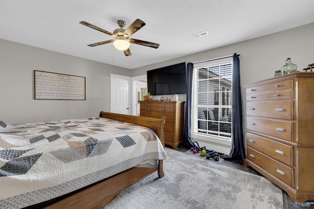 bedroom with ceiling fan, light carpet, and a textured ceiling