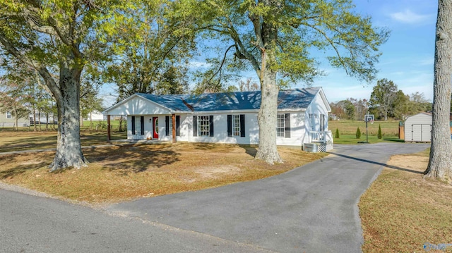 view of front facade with covered porch, a shed, and a front yard