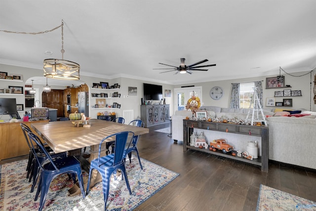 dining space with dark wood-type flooring, ceiling fan with notable chandelier, and ornamental molding