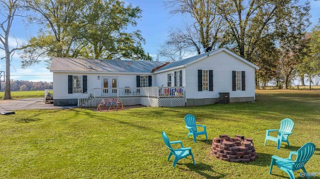 back of house featuring a lawn, french doors, a fire pit, a deck, and central air condition unit