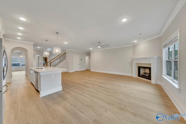 kitchen with a fireplace, light wood-style flooring, light countertops, a ceiling fan, and a sink