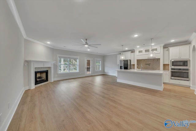 unfurnished living room featuring light wood-type flooring, a ceiling fan, and baseboards