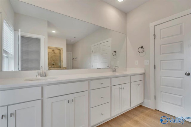 full bath with a stall shower, double vanity, and a sink