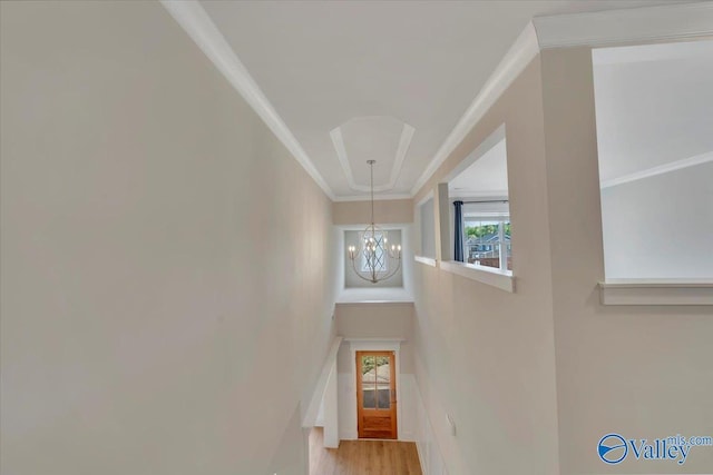 stairway featuring a chandelier, ornamental molding, and wood finished floors