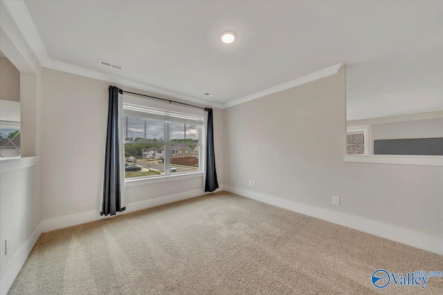 carpeted spare room featuring visible vents, baseboards, and ornamental molding