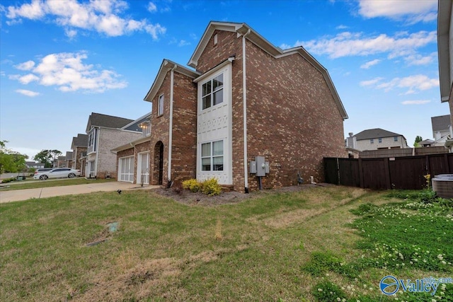 view of property exterior featuring a yard, a garage, fence, brick siding, and driveway