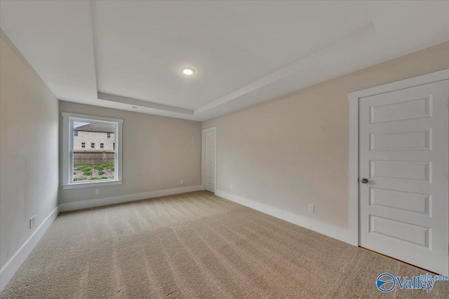 carpeted spare room with a tray ceiling, baseboards, and recessed lighting