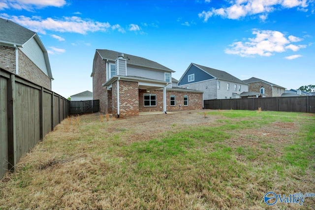 rear view of house featuring brick siding, a fenced backyard, and a yard