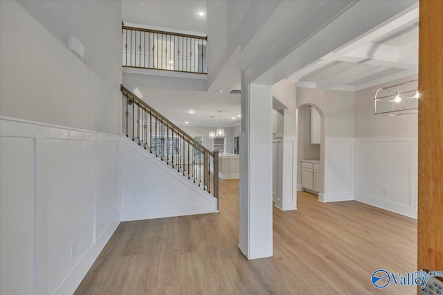 foyer with beamed ceiling, a wainscoted wall, wood finished floors, and stairs