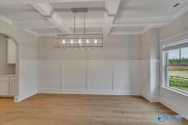 unfurnished dining area featuring coffered ceiling, arched walkways, beamed ceiling, and light wood-style floors
