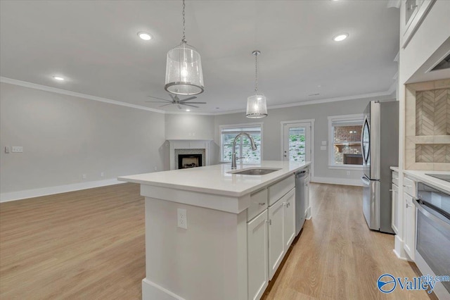 kitchen with light wood-type flooring, white cabinetry, a ceiling fan, appliances with stainless steel finishes, and a sink