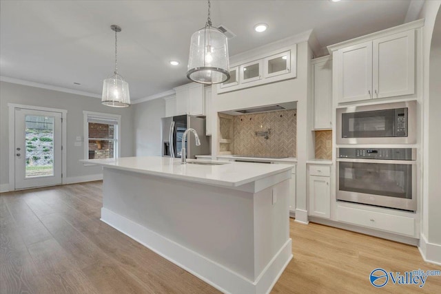 kitchen with crown molding, light countertops, a sink, stainless steel appliances, and backsplash