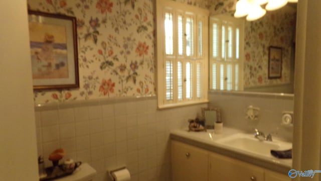 bathroom with vanity, wainscoting, and wallpapered walls