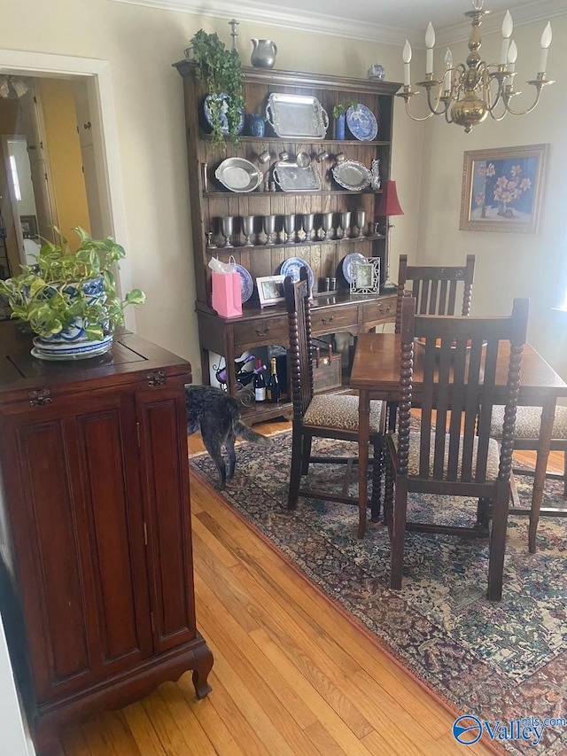 dining area featuring ornamental molding, a notable chandelier, and hardwood / wood-style flooring