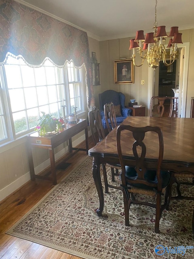 dining space featuring baseboards, ornamental molding, an inviting chandelier, and wood finished floors