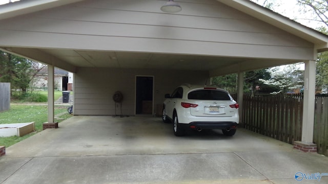 view of parking featuring fence and concrete driveway