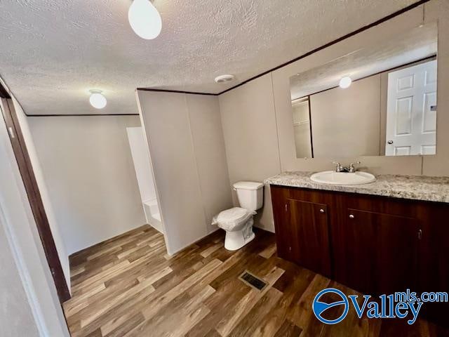 bathroom with hardwood / wood-style floors, toilet, a textured ceiling, and vanity