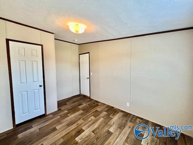 unfurnished bedroom featuring dark wood-type flooring, crown molding, and a textured ceiling