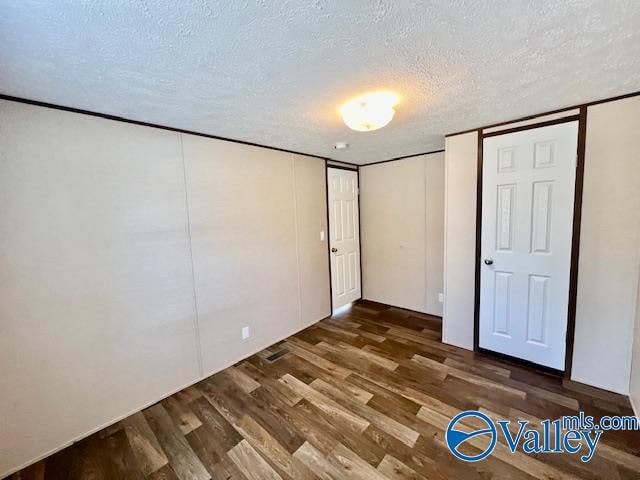 unfurnished bedroom with a textured ceiling and dark hardwood / wood-style floors