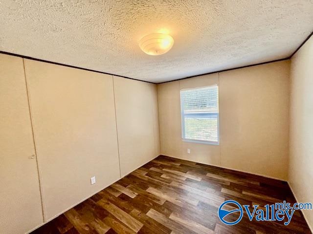 empty room with dark hardwood / wood-style flooring and a textured ceiling