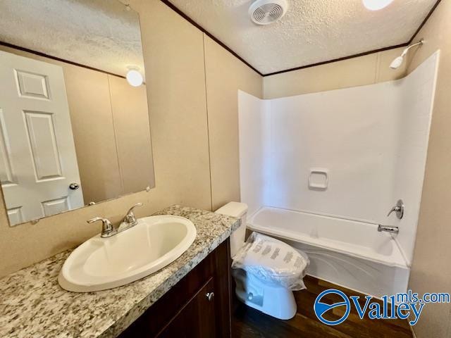 full bathroom featuring a textured ceiling, vanity, hardwood / wood-style floors, toilet, and tub / shower combination